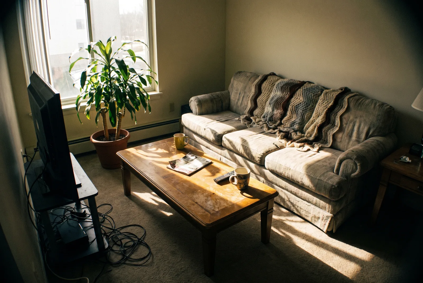 Living room as a raw, dark phone snapshot with cables and clutter